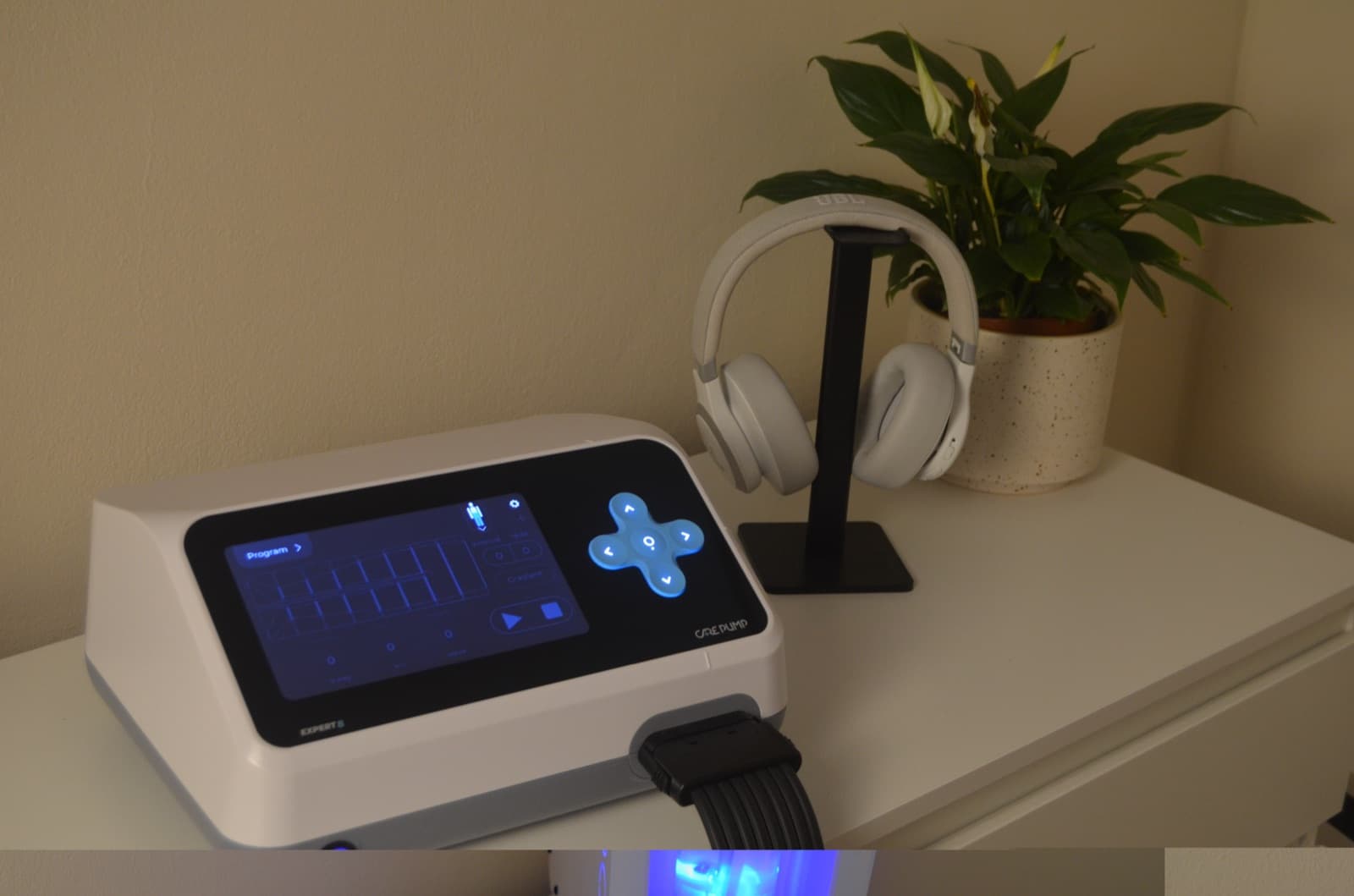 CarePump Steuergerät mit Programmanzeige, Kopfhörer und Pflanze im Studio