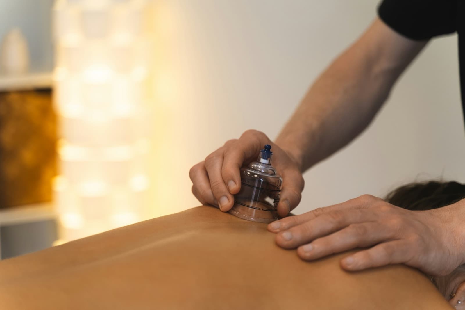 Ein Schröpfglas wird mit der Hand auf den oberen Rücken gesetzt